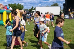 Families and children walk across the KidsFest grounds near inflatables and activity areas during Cape Coral Kiwanis KidsFest 2025.