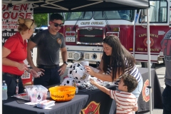 Families visit the Cape Coral Fire Rescue booth in front of a fire engine during Cape Coral Kiwanis KidsFest 2025.