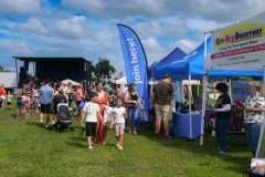 Families walk among vendor booths near the main stage at Cape Coral Kiwanis KidsFest 2025.