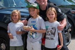 Police officer poses with children beside a patrol vehicle during Cape Coral Kiwanis KidsFest 2025.