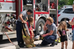 Firefighters assist children with turnout gear demonstrations during Cape Coral Kiwanis KidsFest 2025.