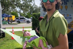Adult dressed as Peter Pan holding a baby in a fairy costume at Cape Coral Kiwanis KidsFest 2025.
