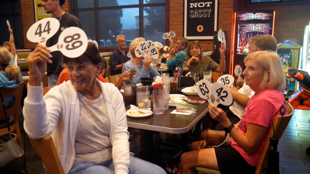 Guests raise bidding paddles during the Rebel Riders Charities quarter auction at Wings and Rings in Fort Myers, Florida.