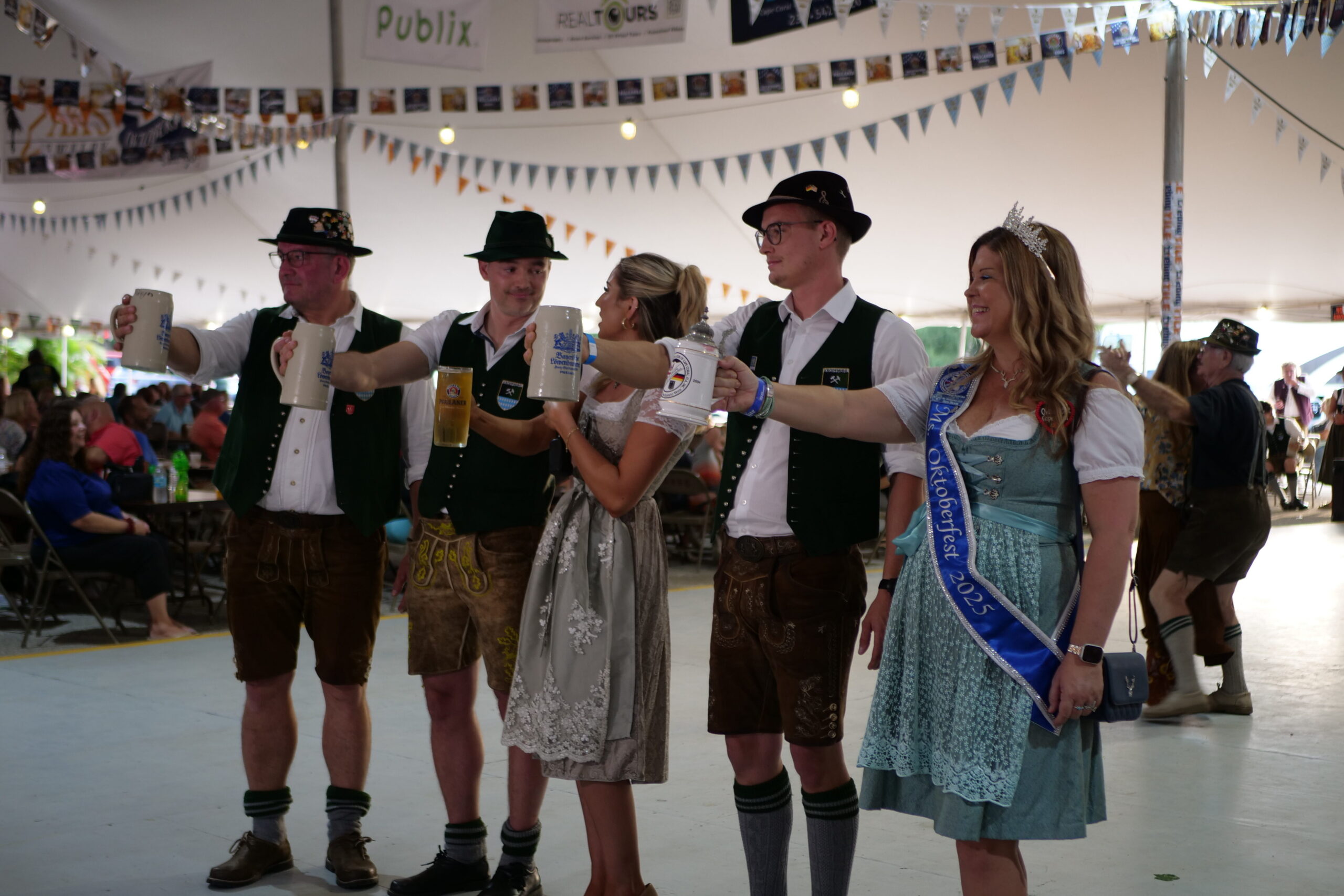 Group of Oktoberfest participants in Lederhosen and Dirndls holding traditional beer steins during the 40th Annual Oktoberfest at the German-American Social Club of Cape Coral.