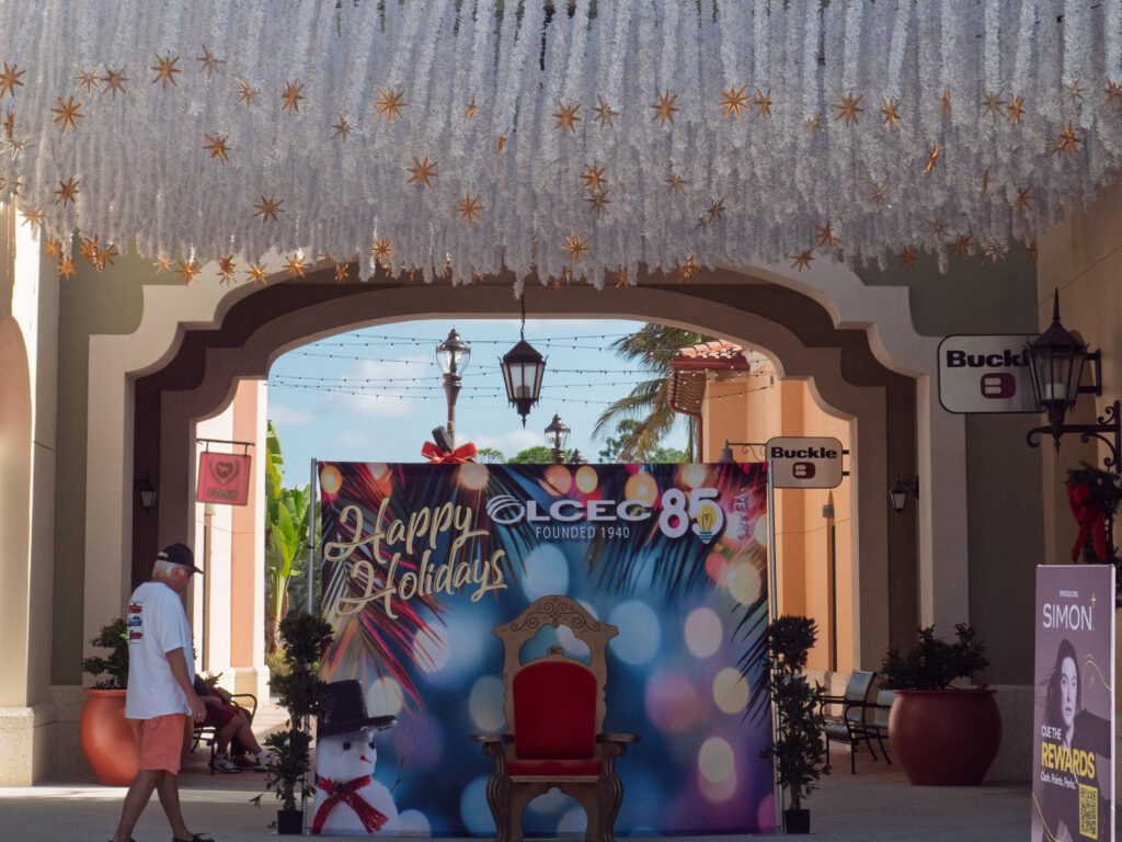 Holiday photo backdrop and Santa chair displayed beneath festive white hanging decorations at Coconut Point during the Holiday Celebration in Estero, Florida.
